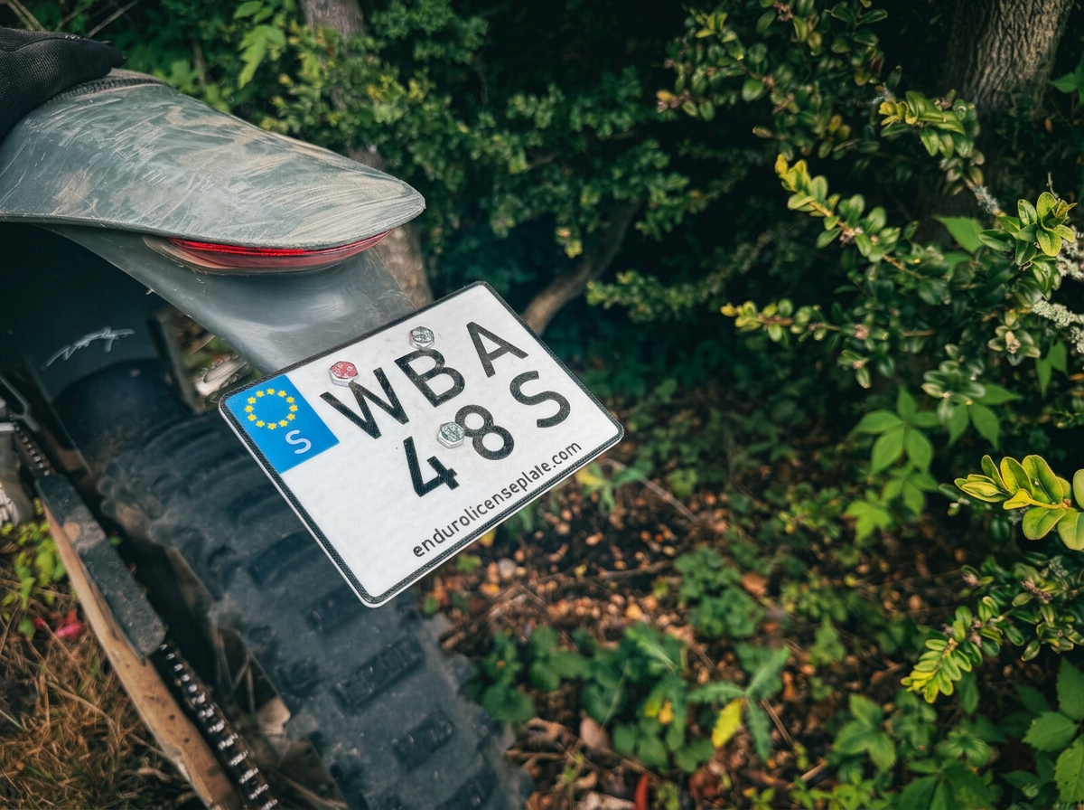 Flexible enduro license plate mounted on a dirt bike rear fender in the woods